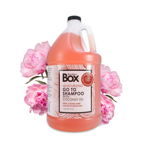 Gallon jug of BatherBox® Go To Shampoo displayed with pink peony flowers