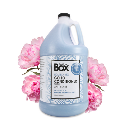 Gallon jug of BatherBox® Go To Conditioner displayed with pink peony flowers