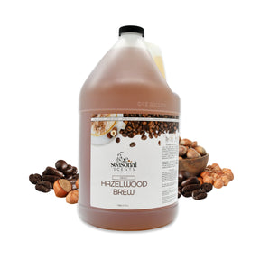 Gallon jug of Seasonal Scents Hazelwood Brew Shampoo, displayed with fresh hazelnuts and coffee beans