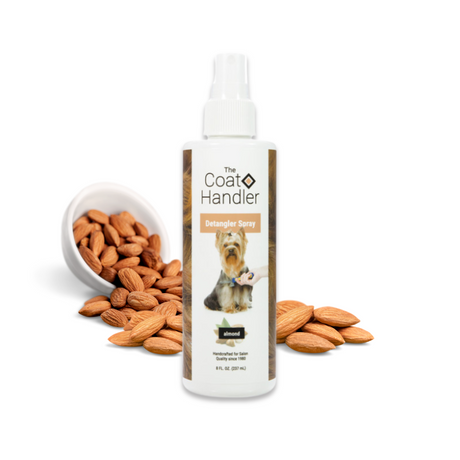 8 oz bottle of The Coat Handler Detangler Spray displayed with whole almonds spilling from a white bowl